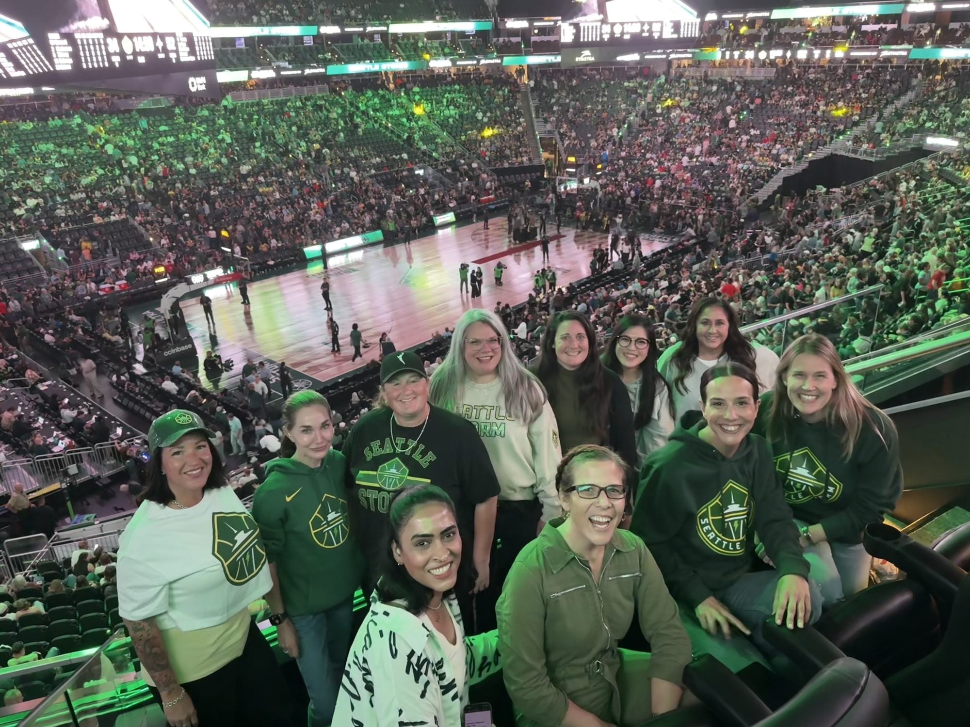 Guests of the Women in Cyber night in the suite at Climate Pledge Arena, with the Seattle Storm court behind them